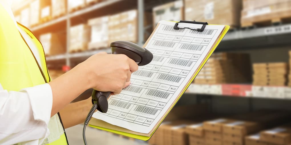 Worker checking and scanning package codes by laser rf scanner in modern warehouse.